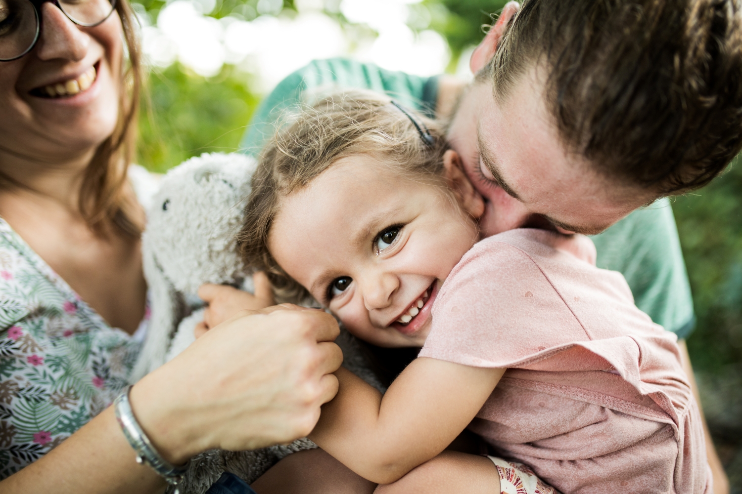 enfant souriant et parents faisant un câlin